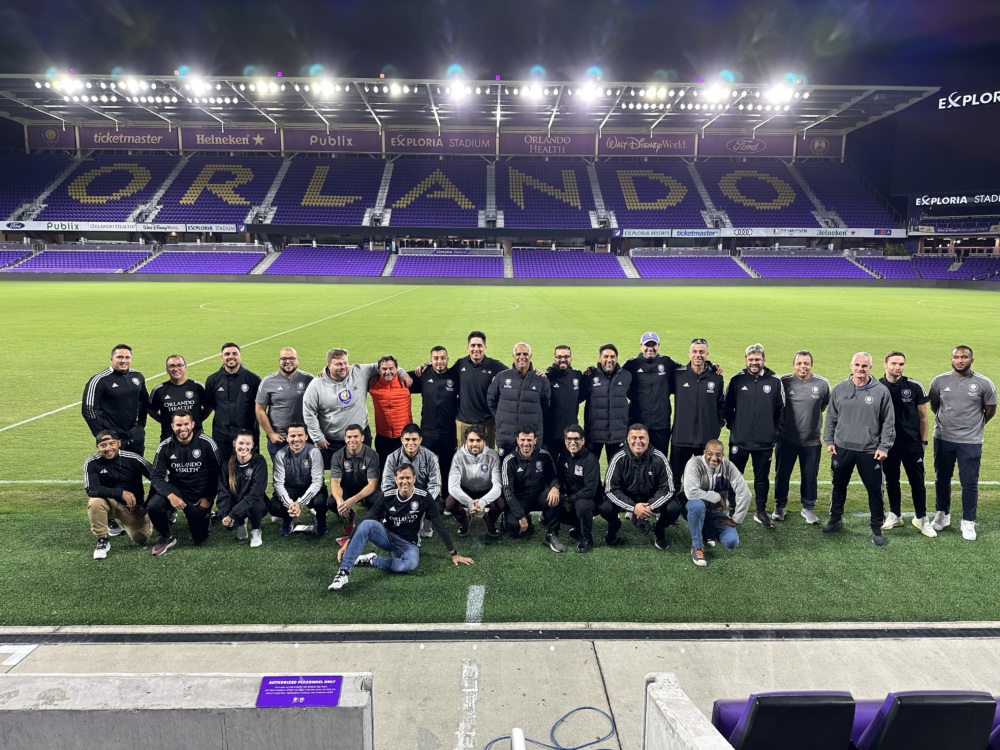 A group of Orlando SC coaches pose for a photo on the field at the Orlando City SC stadium